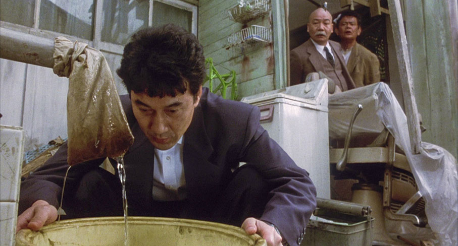 Takuro converses with his eel as Nakajima and Takada watch curiously on