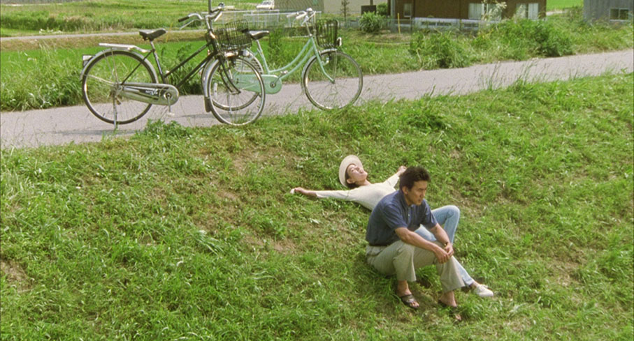 Takuro sits uncomfortably forward as Keiko lies back and enjoys the sunshine