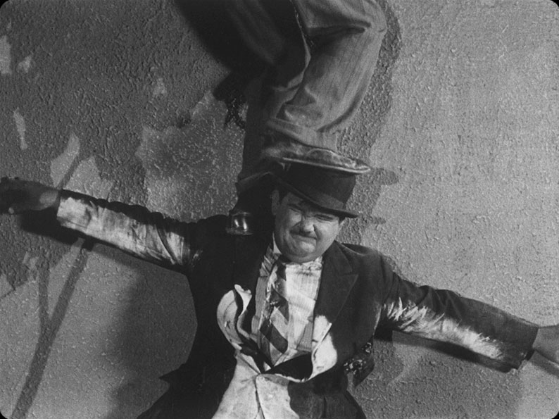 Ollie helps Stan climb the cemetery wall in Habeas Corpus