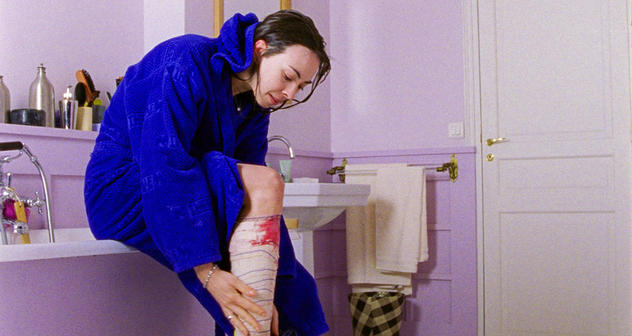 Esther examines her bandaged leg in Sandrine's bathroom