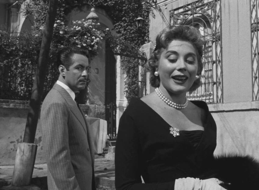 Patricia cheerily recalls their past association whilst a less than happy Archibaldo looks on